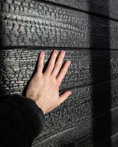Main touchant un mur de Shou Sugi Ban