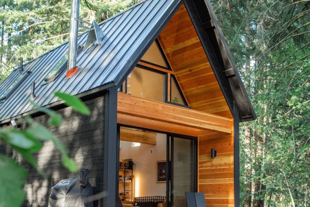 Maison en bois noir avec des détails clairs et contrastés au milieu d'une forêt
