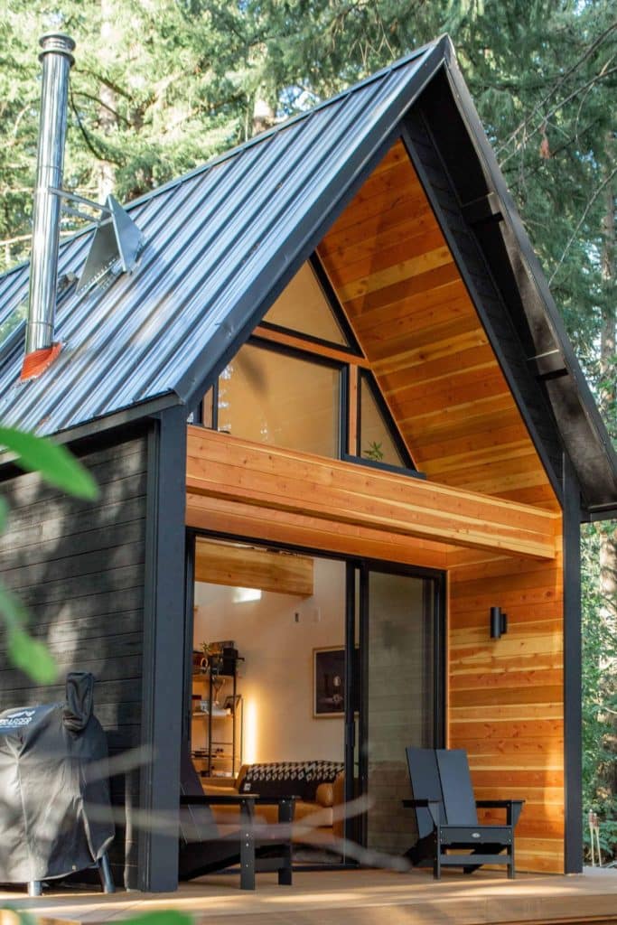 Vue latérale d'une maison dont la façade en bois noir est rehaussée de bois clair