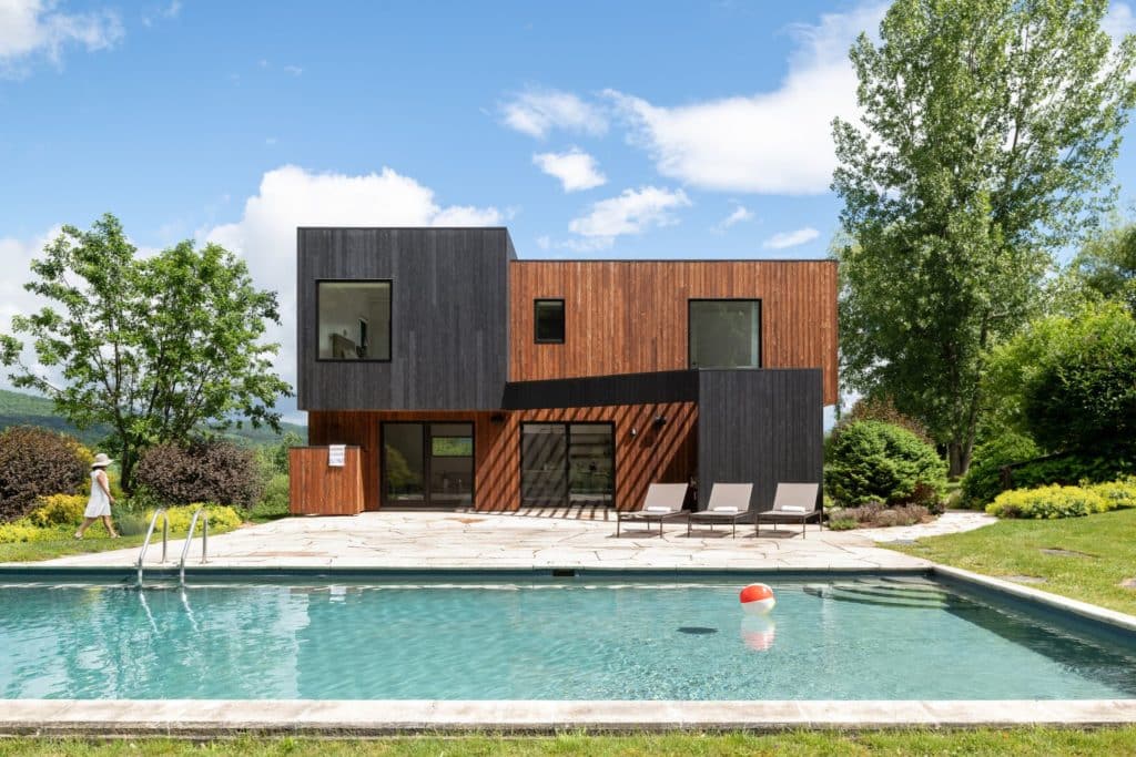 Maison avec une façade noire et marron clair et une grande piscine à l'avant
