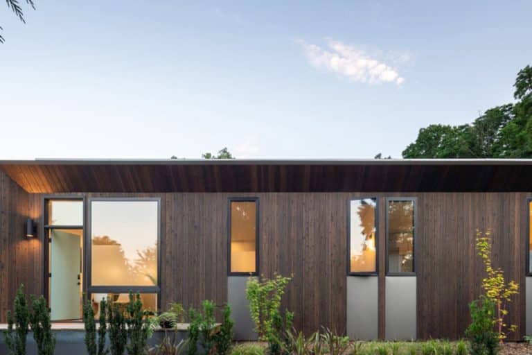 Bungalow with light brown wooden facade and lighted windows