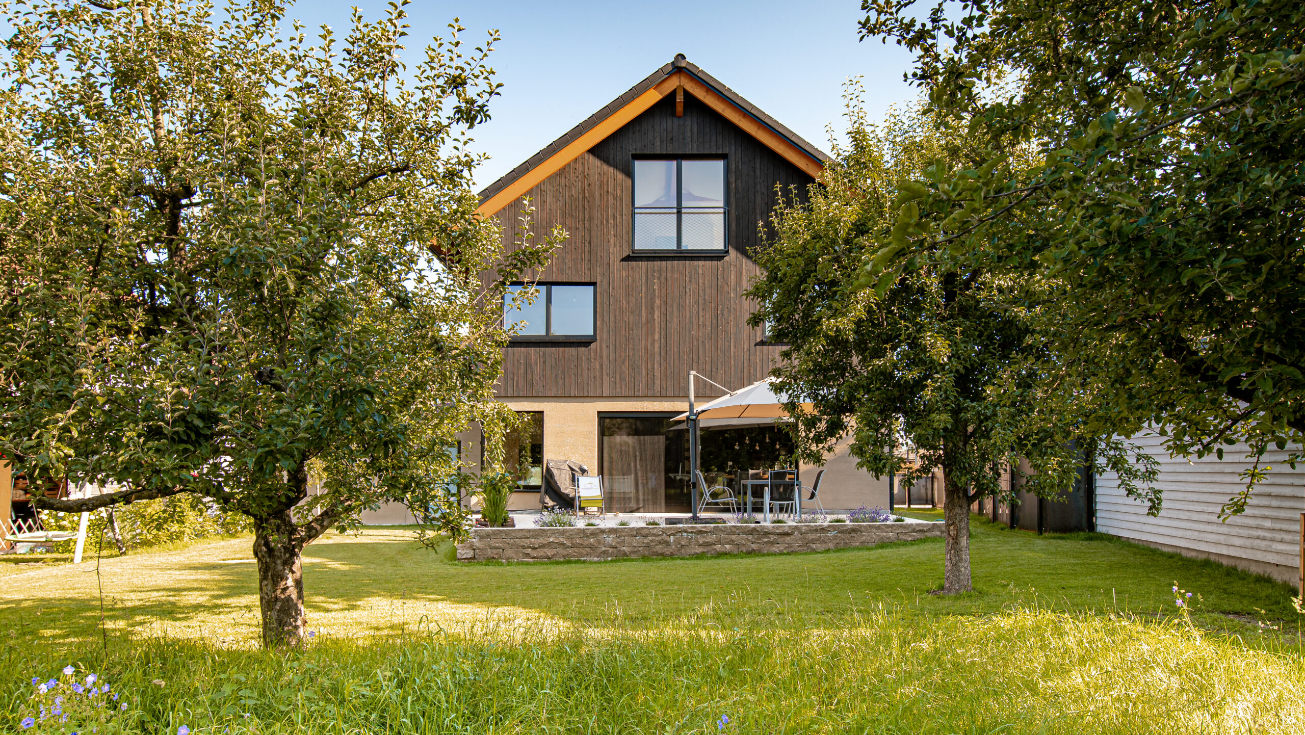Vue arrière d'une maison bardée en Gendai avec arbres de jardin