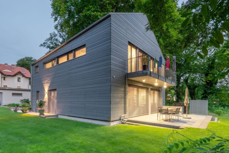 Maison avec revêtement Gendai gris devant des arbres et avec pelouse